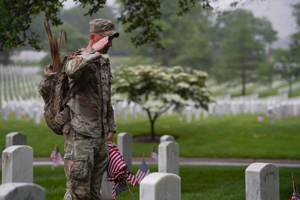 A soldier saluting the grave of a fallen soldier.